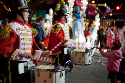 Drummers in silver costumes marching under falling snow on Bellevue Way.